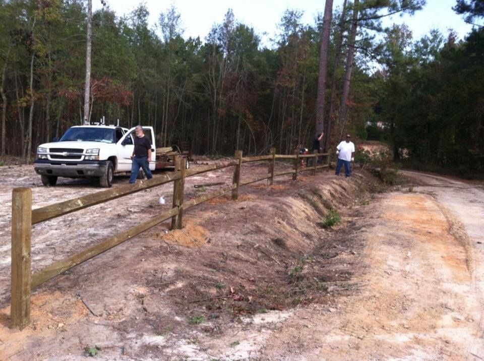 A white truck is parked next to a wooden fence