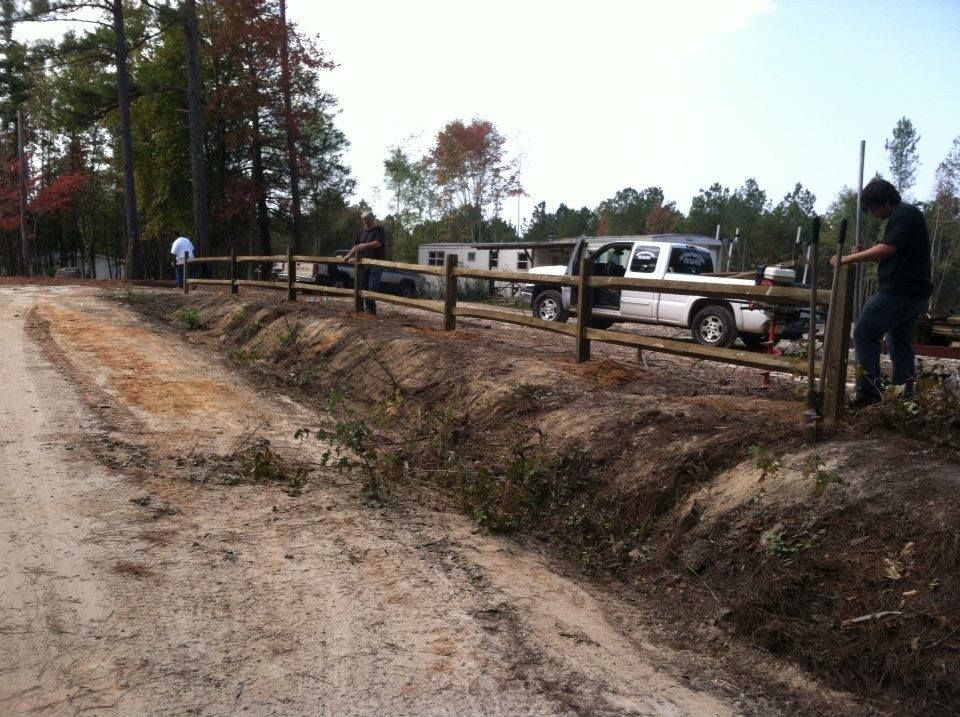 A white truck is parked behind a wooden fence