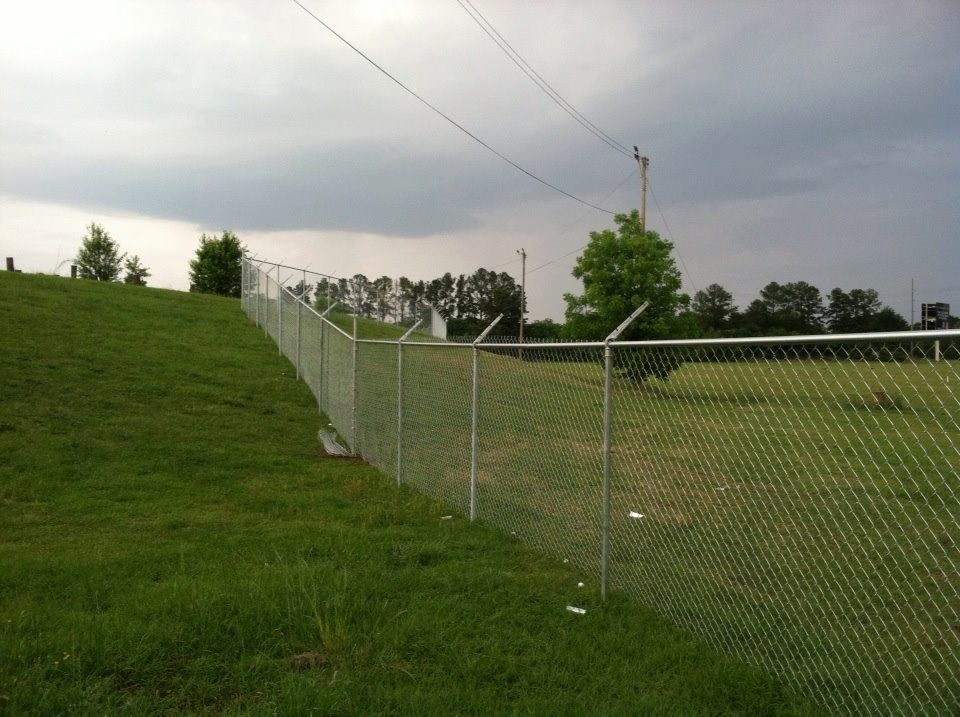 A chain link fence surrounds a grassy field