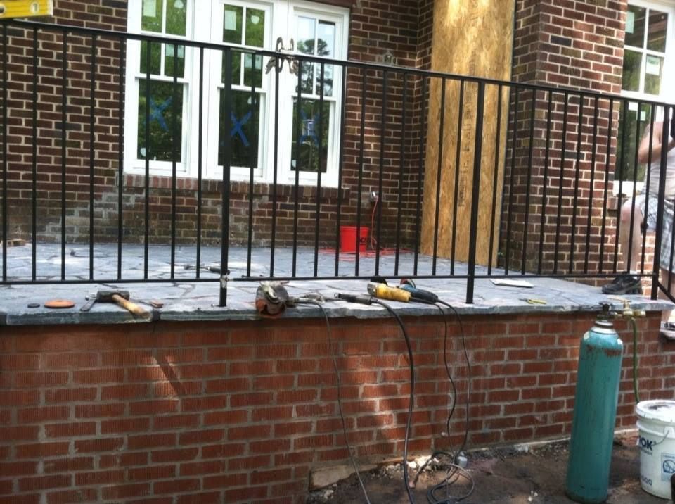 A brick wall with a metal railing in front of it