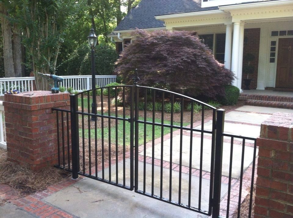A black wrought iron gate is in front of a house
