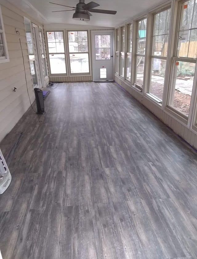 A large room with a lot of windows and a ceiling fan.