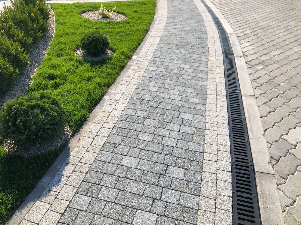 stone paver sidewalk beside landscaping with drainage system installed