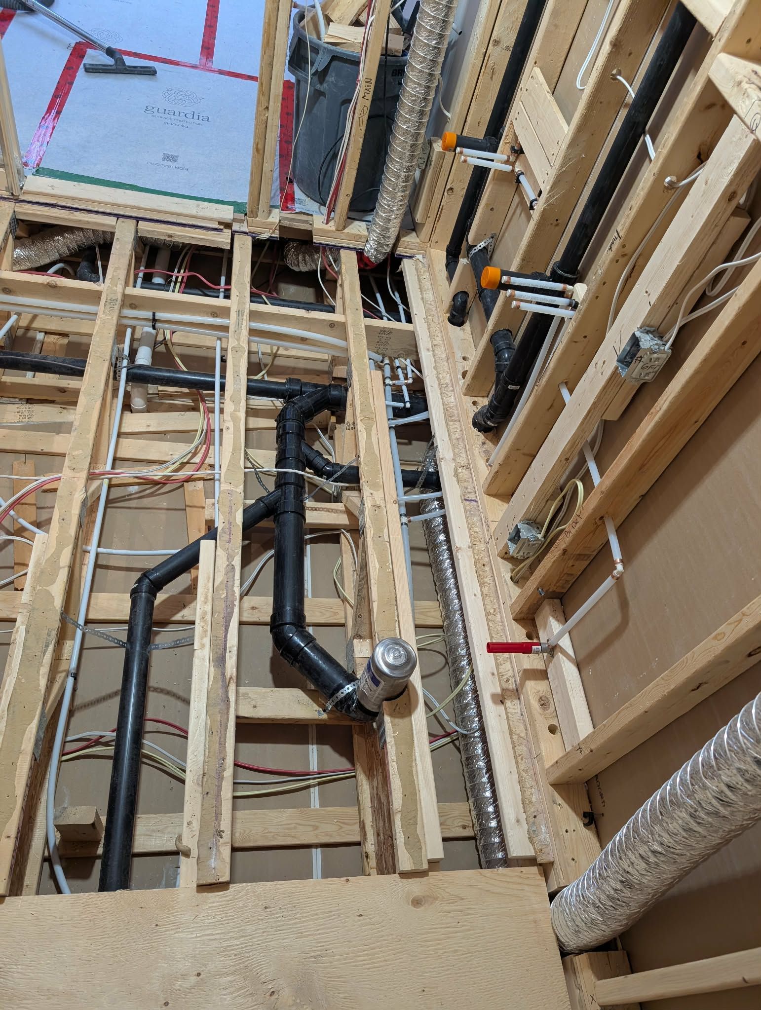 Mise en place des installations de plomberie et d'électricité dans le sol et les murs d'un bâtiment, montrant les tuyaux et les câbles.