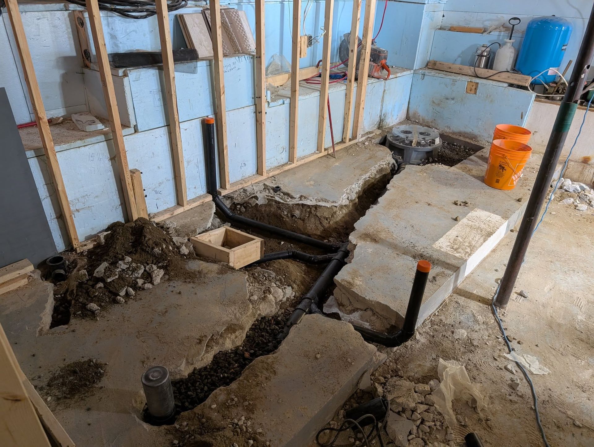 Rénovation du sous-sol avec tuyauterie apparente, béton et charpente. Travaux en cours.