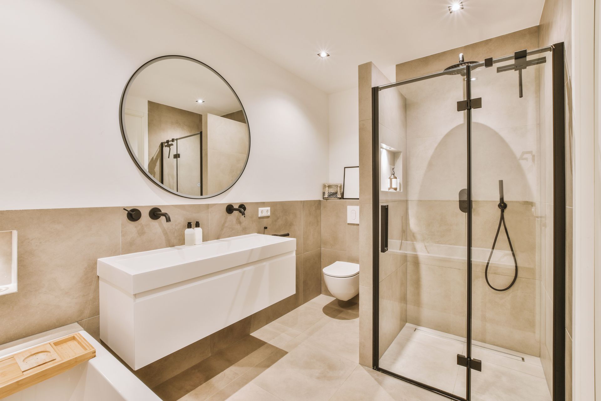 Salle de bains moderne avec meuble-lavabo blanc, miroir rond et douche en verre.
