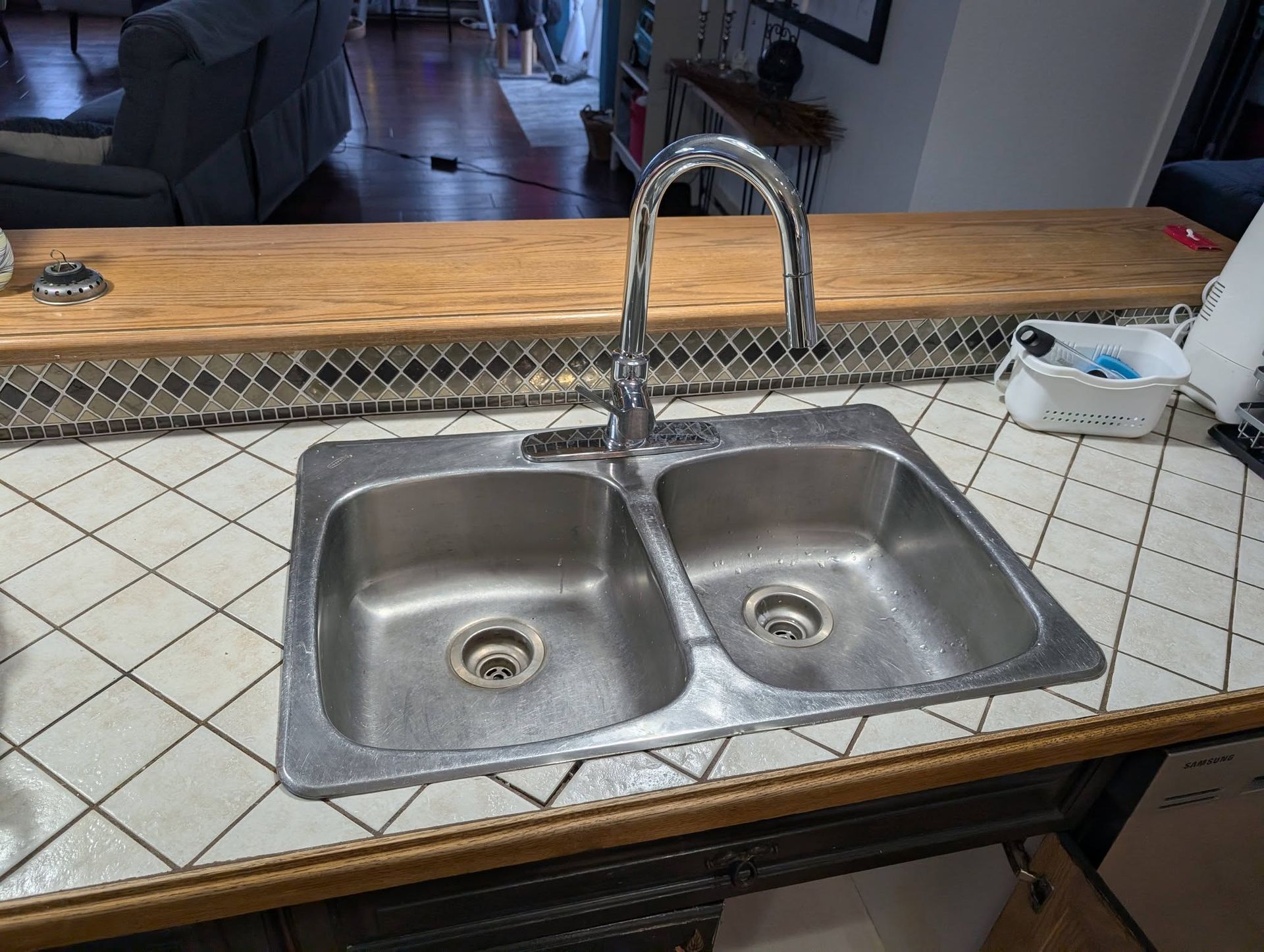 Évier double en acier inoxydable avec robinet chromé sur un plan de travail carrelé.