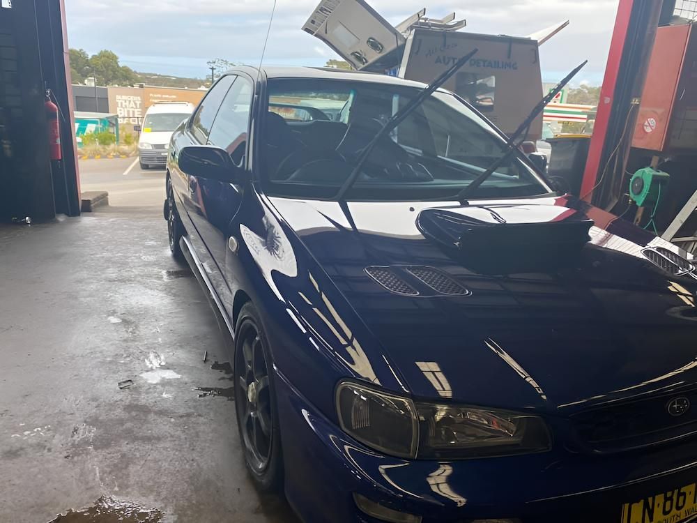 A Blue Car With The Hood Up Is Parked In A Garage — All Clean Auto Detailing In Caves Beach, NSW