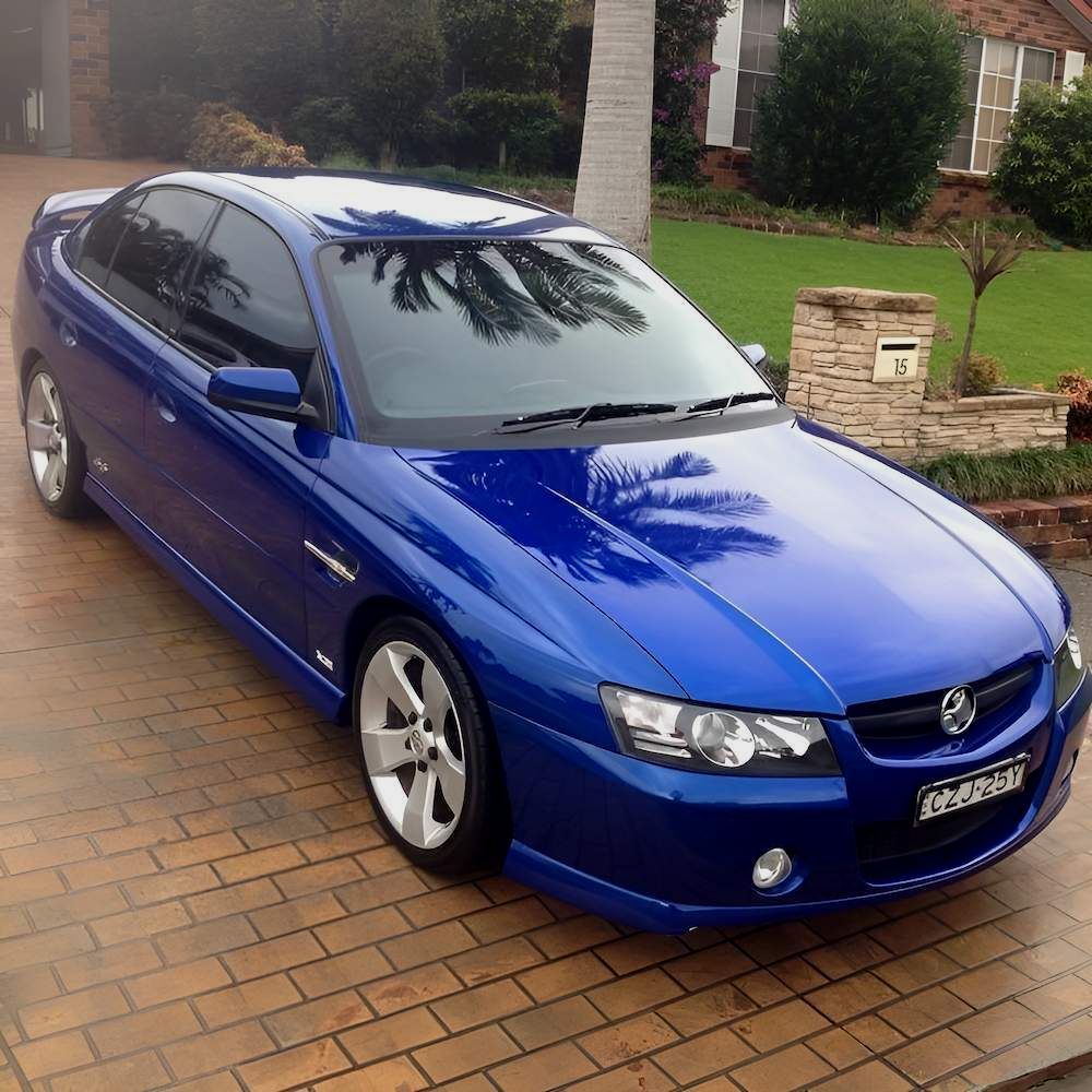 A Blue Car Is Parked On A Brick Driveway In Front Of A House — All Clean Auto Detailing In Caves Beach, NSW