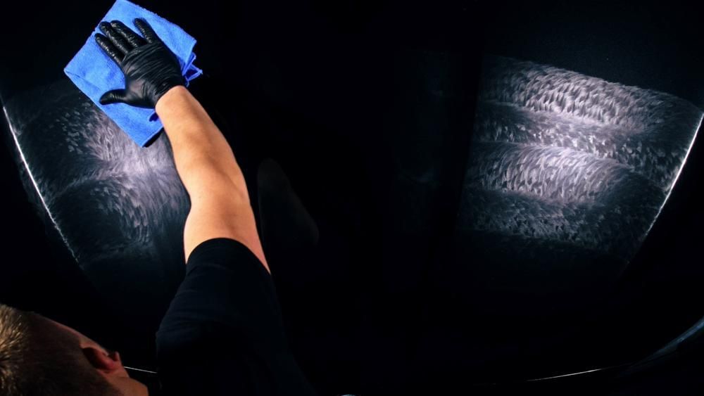 A Man Is Cleaning A Car Windshield With A Cloth — All Clean Auto Detailing In Summerland Point, NSW