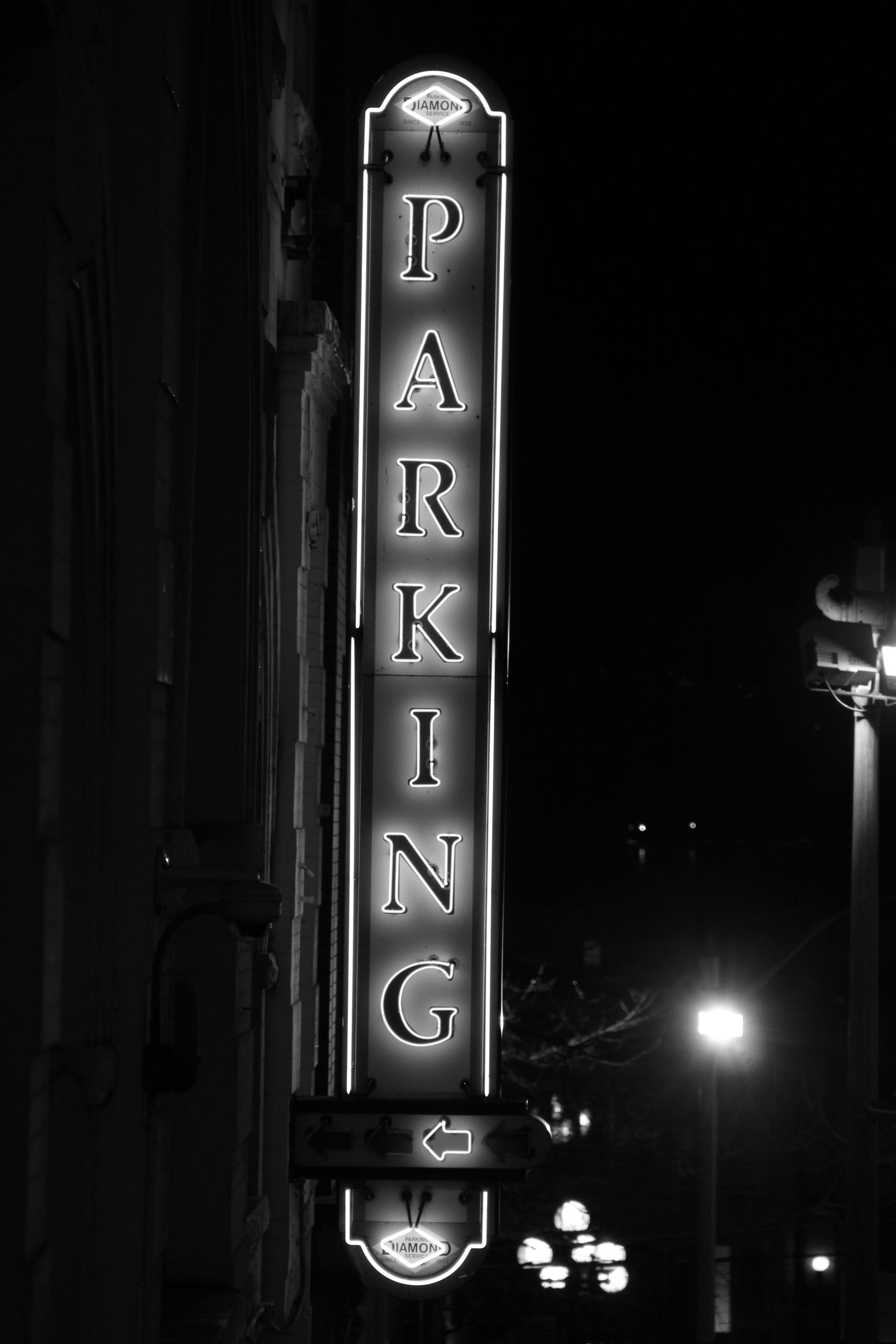 A black and white photo of a neon sign that says parking
