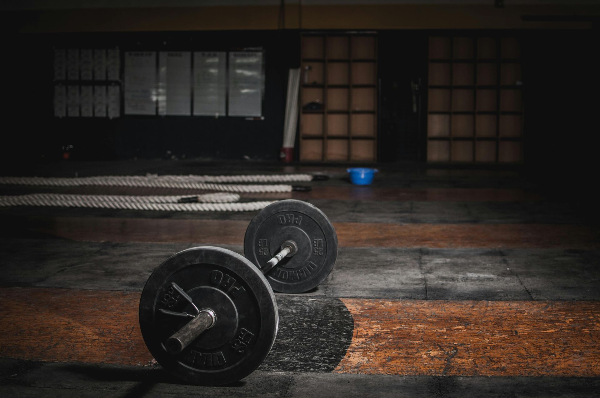 Two barbells are sitting on the floor in an empty gym.