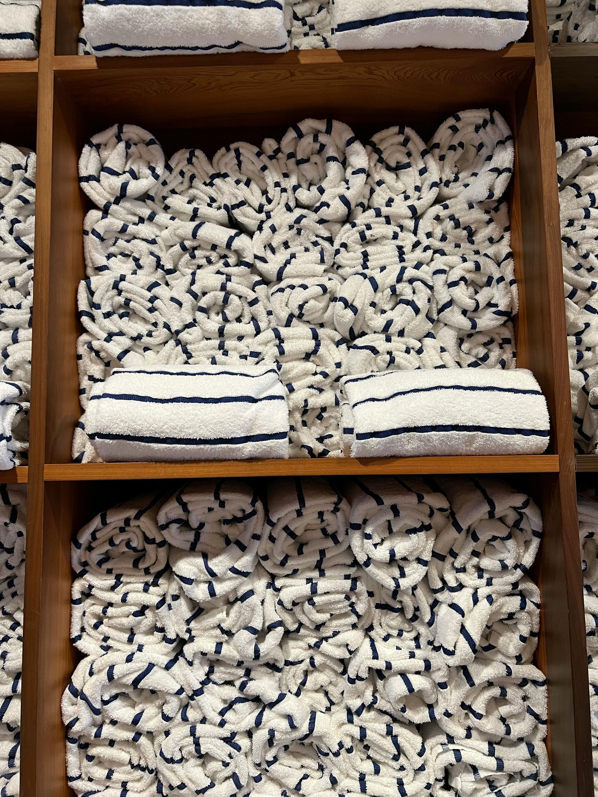 A bunch of towels are stacked on a wooden shelf
