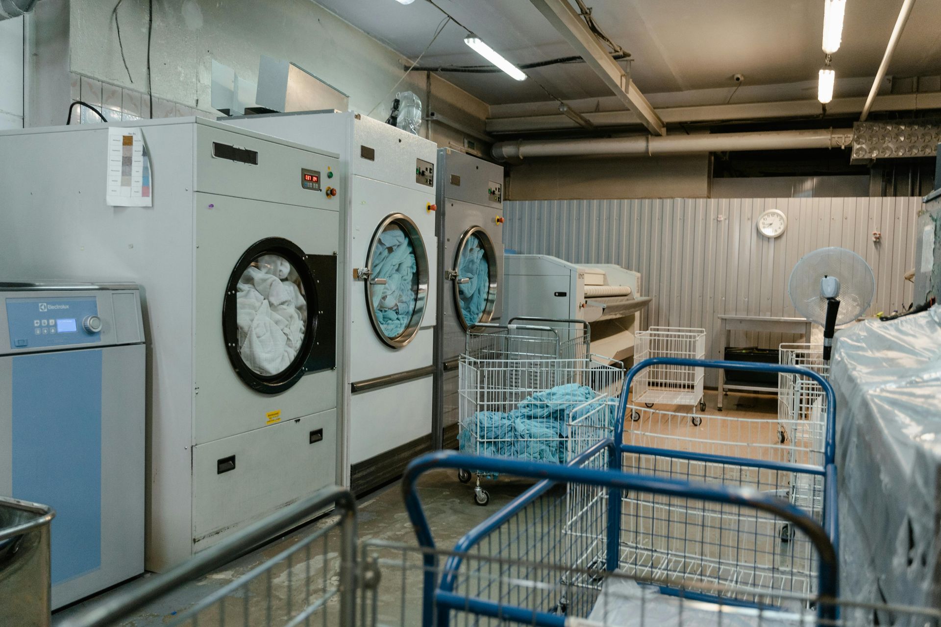 A laundry room filled with lots of washing machines and carts.