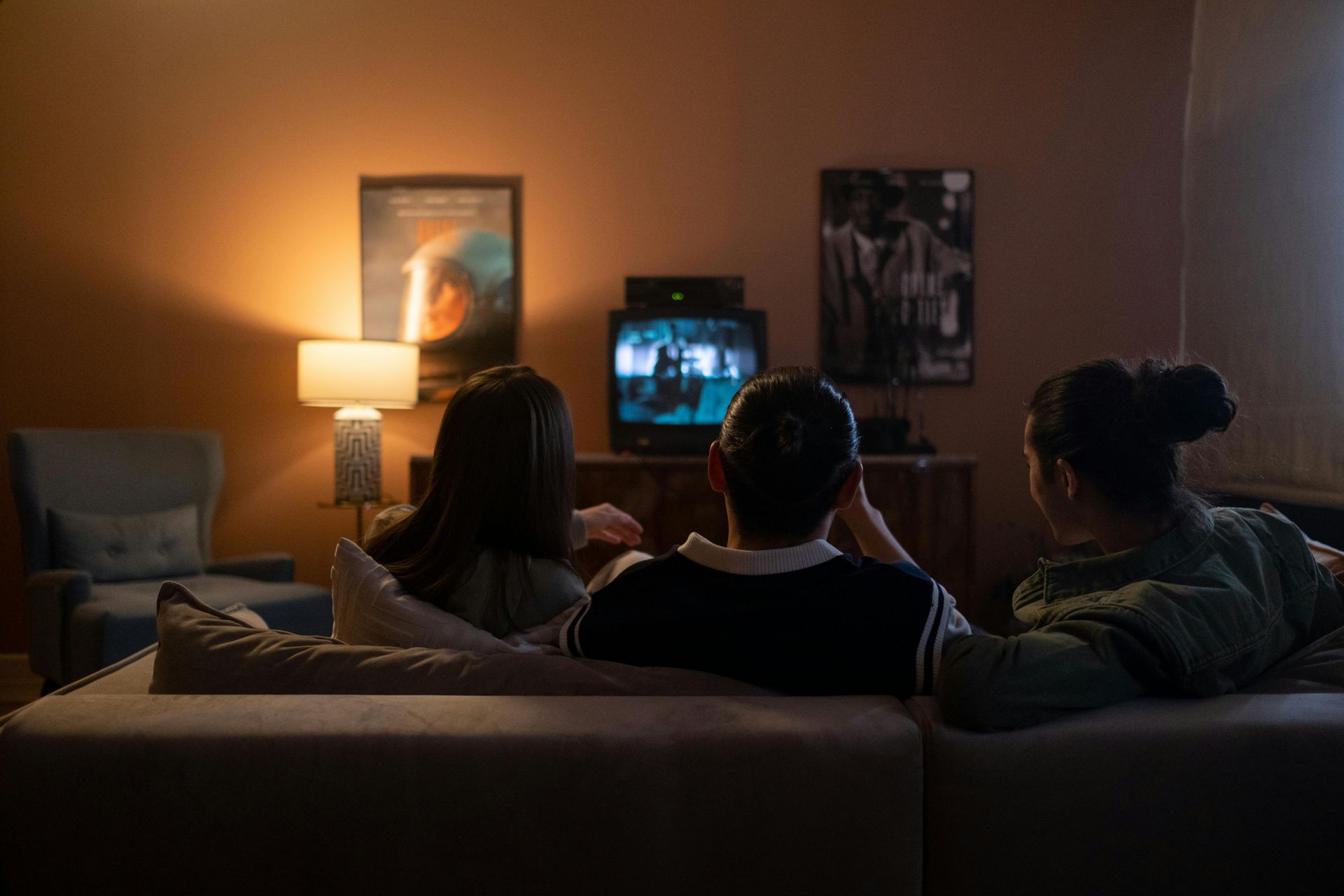 A group of people are sitting on a couch watching a television.