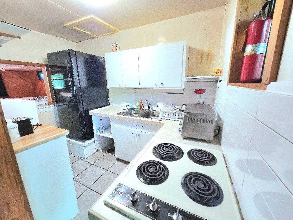 A kitchen with a stove , sink , refrigerator and fire extinguisher.