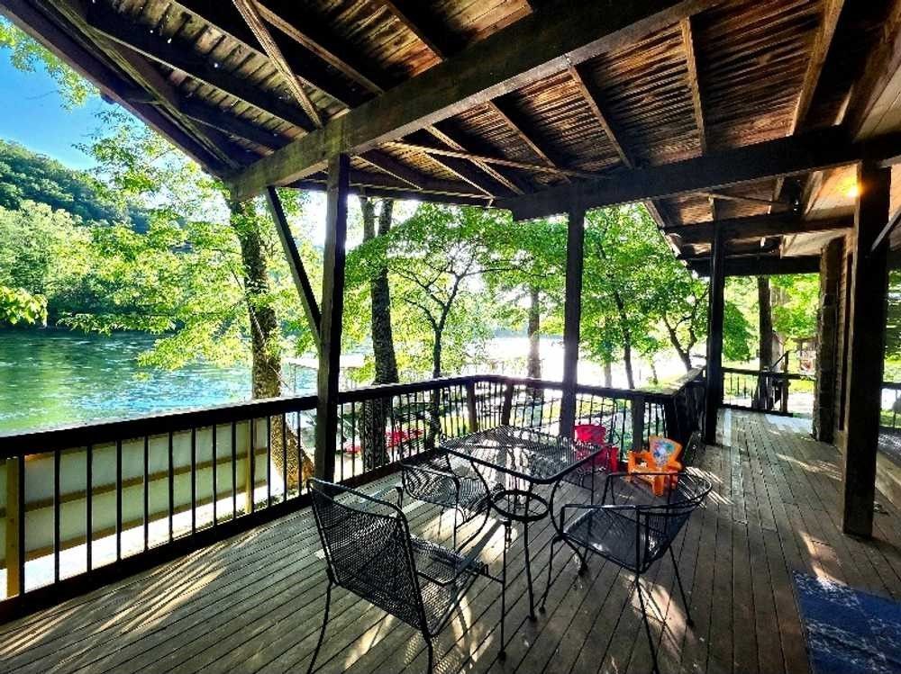 A large wooden deck with a table and chairs overlooking a lake.