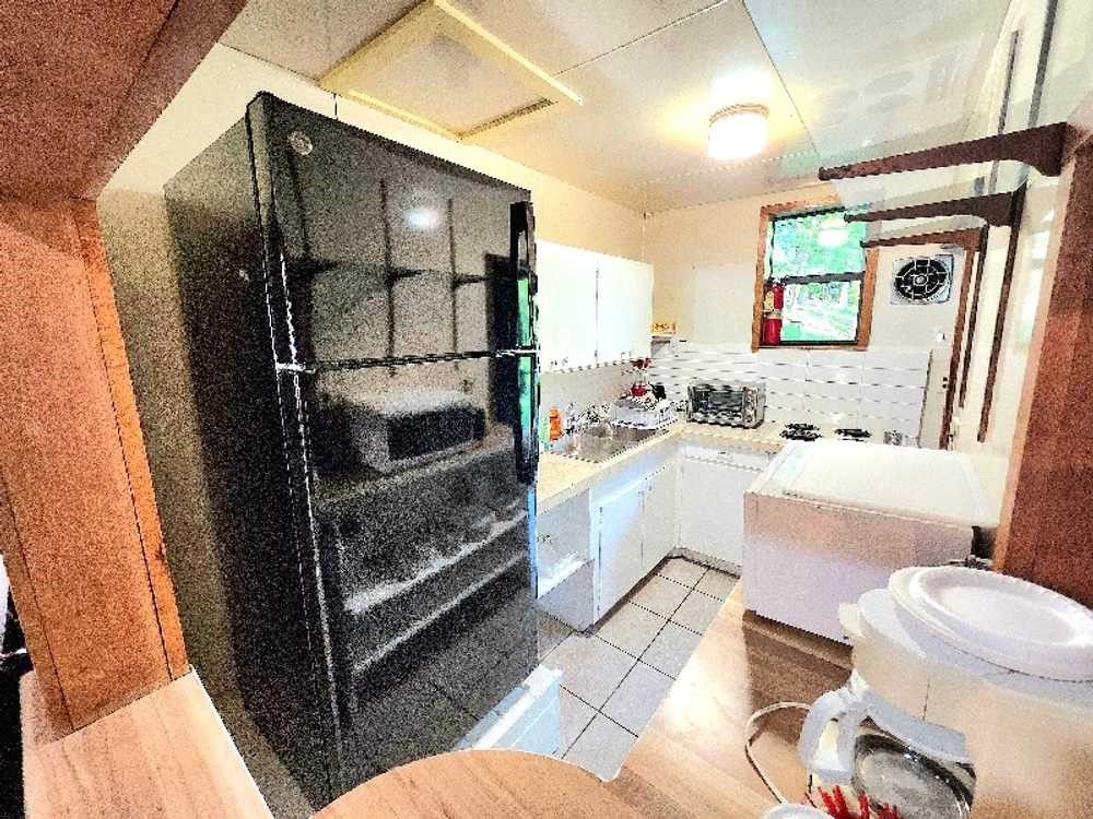 A kitchen with a black refrigerator and white cabinets.