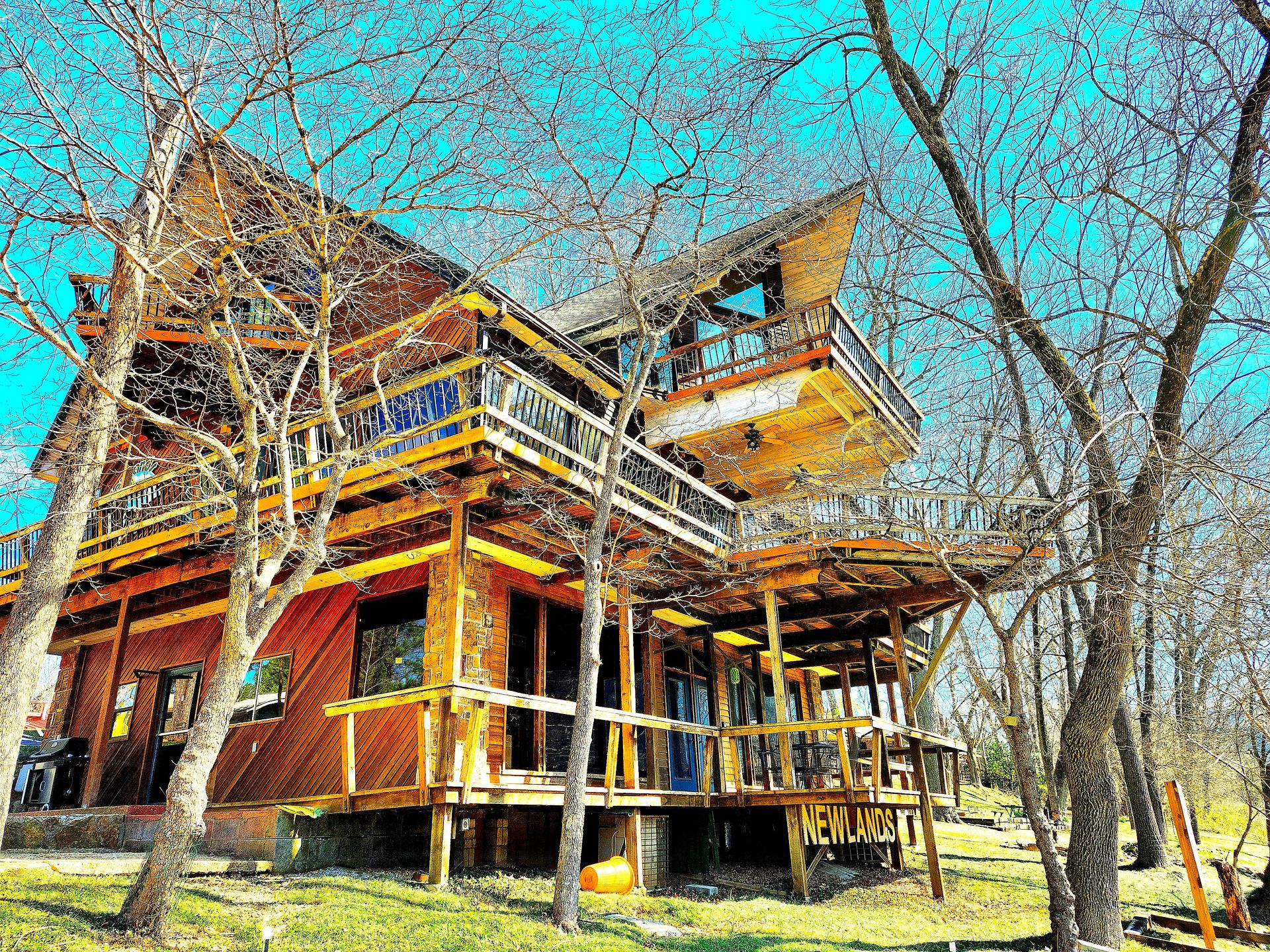 A large wooden house is surrounded by trees on a sunny day.