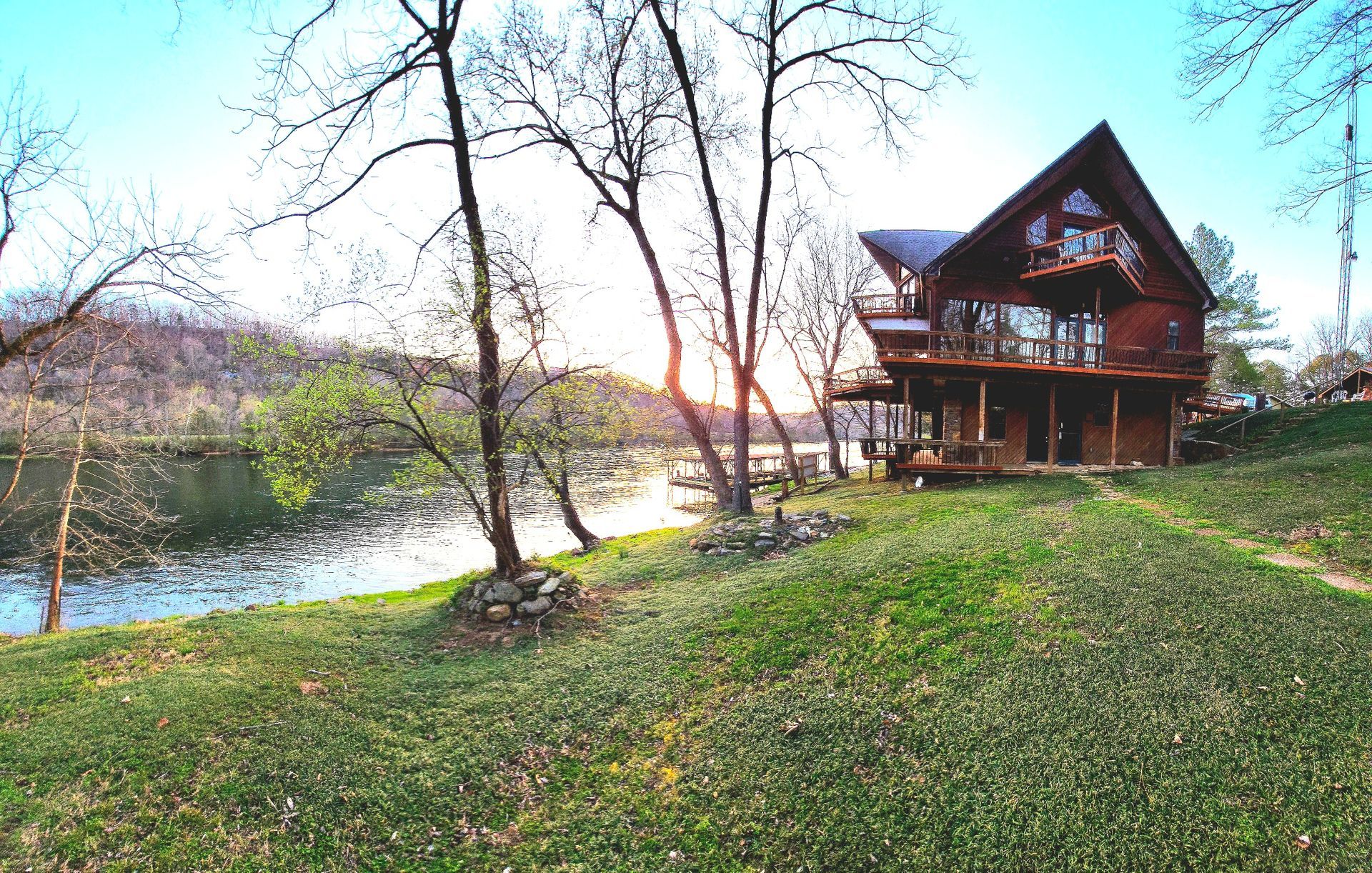 A large log cabin is sitting next to a lake surrounded by trees.