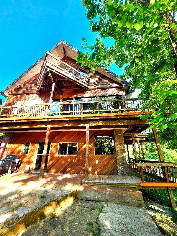 A large wooden house with a large deck and stairs leading up to it.