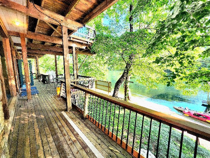 A wooden deck with a railing overlooking a lake.