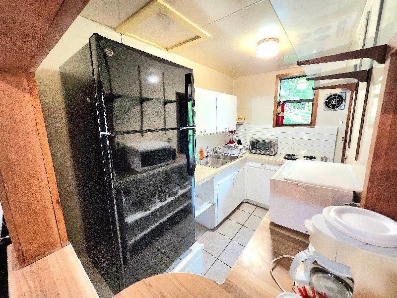 A kitchen with a black refrigerator and white cabinets