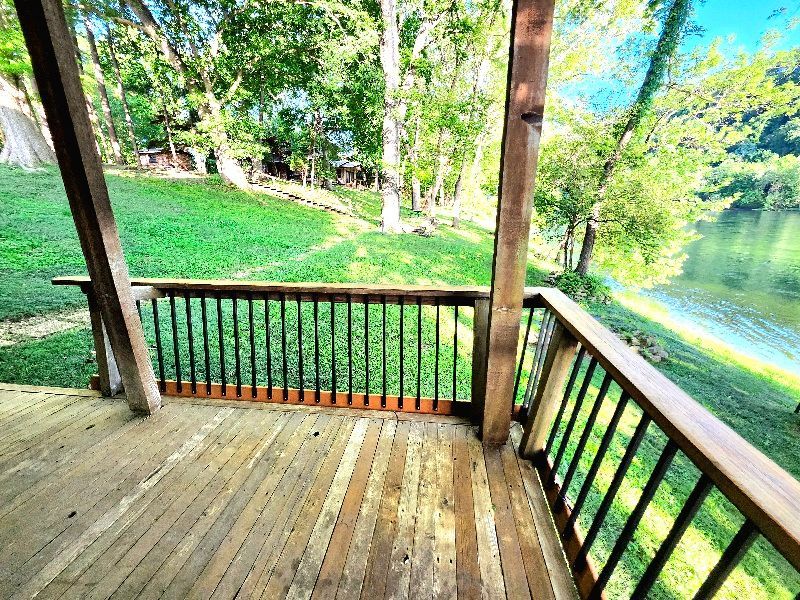 A wooden deck with a view of a lake and trees.