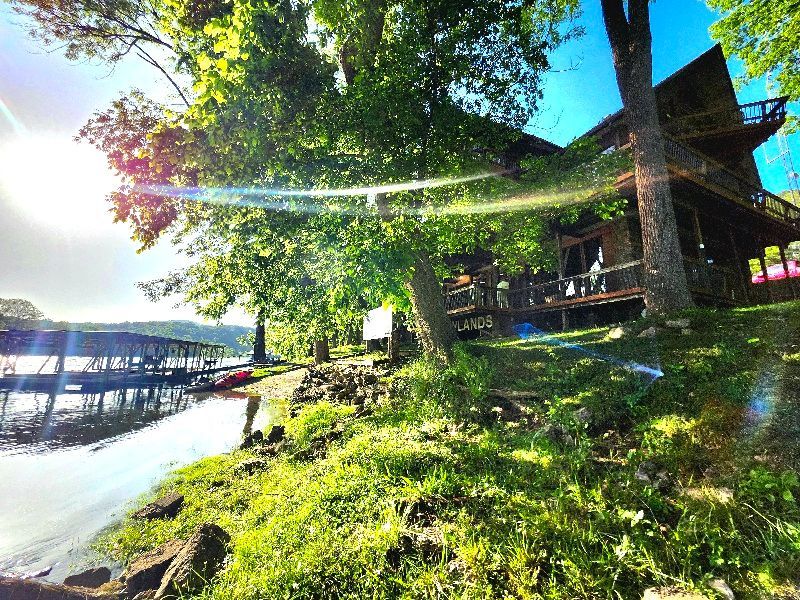 A house is sitting on the shore of a lake next to a body of water.