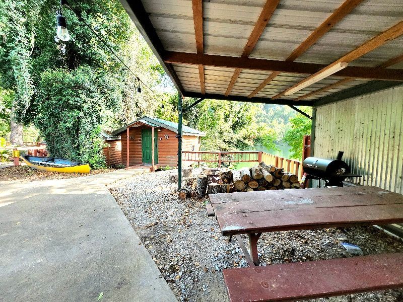 covered patio with firewood, smoker, and picnic table on white river at copper johns resort