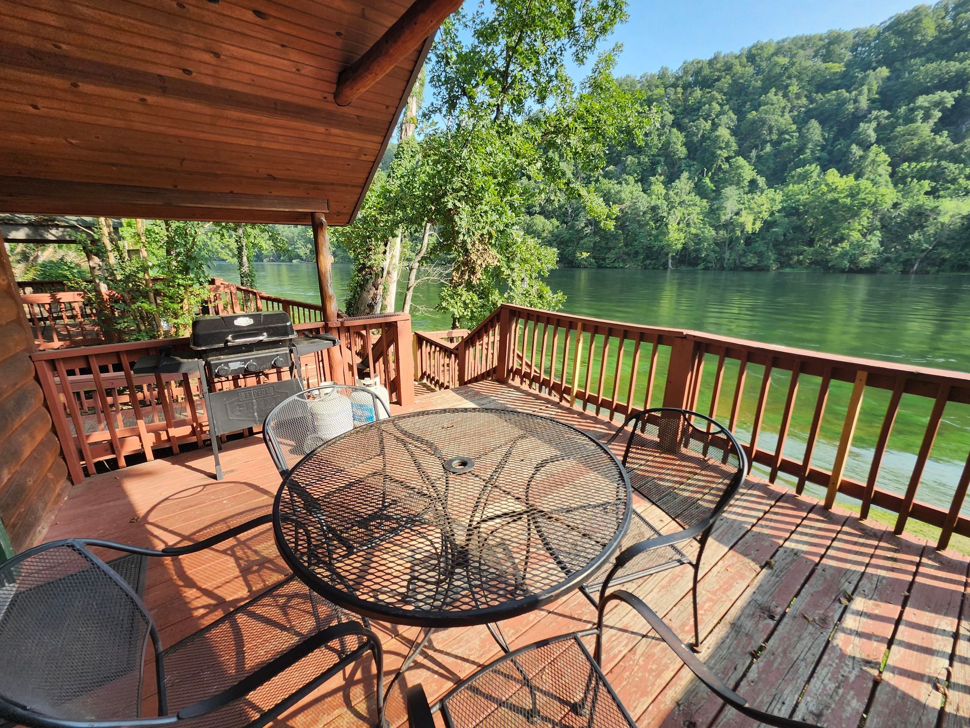 covered deck with propane grill, table and chairs on bank of white river copper johns cabin 4