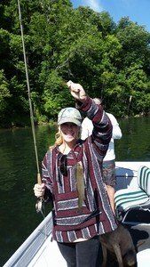 A woman is holding a fish in her hand while fishing on a boat.