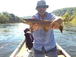 A man in a boat is holding a fish in his hands