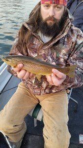 A man with a beard is sitting on a boat holding a fish.