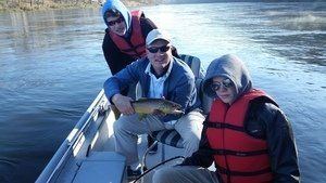 A group of people in a boat holding a fish