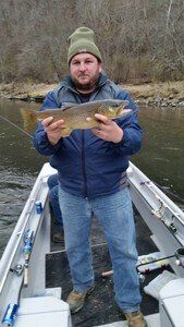 A man is standing in a boat holding a large fish.