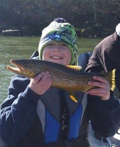 A young boy is holding a brown trout in his hands