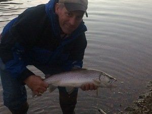 A man is holding a fish in his hands in the water.