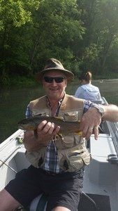 A man is sitting on a boat holding a fish.