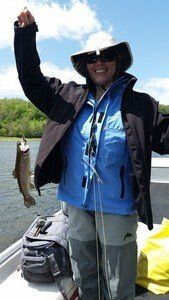 A woman is holding a fish in her hand on a boat