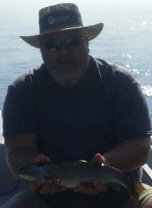 A man in a hat is holding a fish in his hands