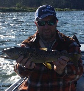 A man in a plaid shirt is holding a fish in his hands