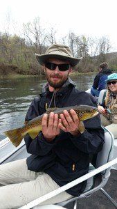 A man is sitting in a boat holding a fish in his hands.