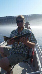 A man is sitting on a boat holding a fish.