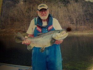 A man in overalls is holding a large fish in his hands.