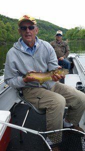 A man is sitting on a boat holding a fish.