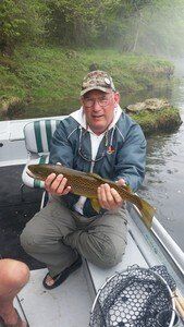 A man is sitting on a boat holding a fish.