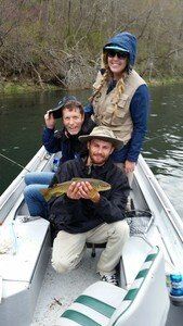 A group of people are sitting on a boat holding a fish.