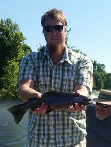 A man in a plaid shirt is holding a fish in his hands