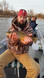 A man is sitting on a boat holding a fish in his hands.